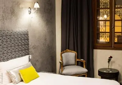 a bedroom with a chair and a bed with a yellow pillow at Riad Yacout in Meknès