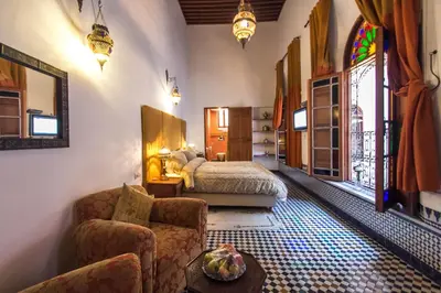 a bedroom with a bed and a couch and a chair at Riad Fez Yamanda in Fès