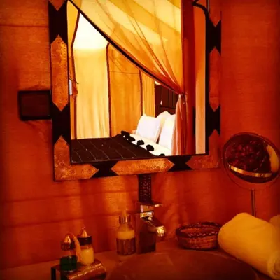 a bathroom with a mirror and a bed in a room at Original Luxury Camp in Merzouga