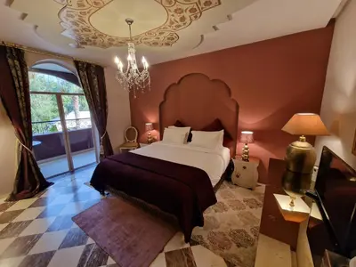 a bedroom with a large bed and a chandelier at Palace Africa - Marrakech Palmeraie in Marrakech
