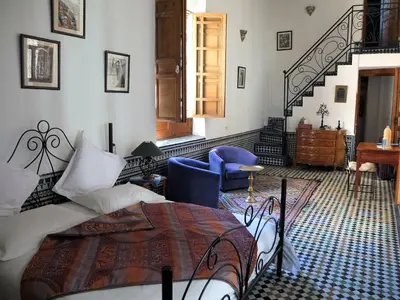 a bedroom with a bed and a blue chair at Riad La Clé De Fès in Fès