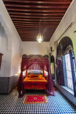 a bedroom with a bed in the corner of a room at Riad Hala in Fès