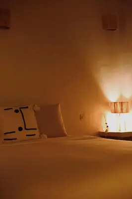 a bedroom with a white bed with a light on it at Kasbah des cyprès in Skoura