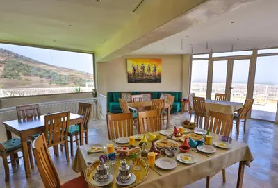 a dining room with tables and chairs and windows at Bhalil Farm House in Sefrou