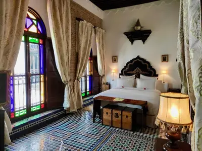 a bedroom with a bed and stained glass windows at Riad Le Calife in Fès