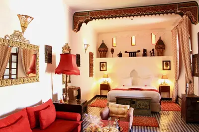 a bedroom with a bed and a red couch at Riad Le Calife in Fès