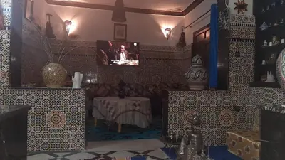 a room with a table and a tv on a wall at Mini Riad family Chez Adil Batha Fés in Fès