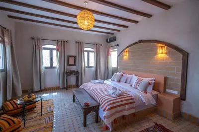 a bedroom with a large bed and a brick wall at Riad Jouba in Merzouga