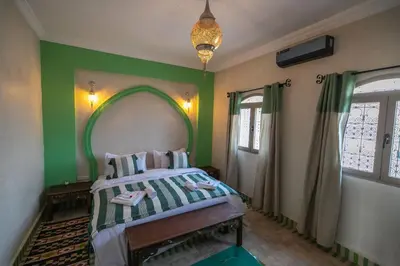 a bedroom with a bed with a green wall at Riad Jouba in Merzouga