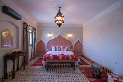 a bedroom with a bed and a chandelier at Riad Jouba in Merzouga