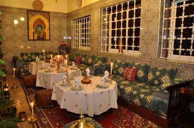 a restaurant with two tables and a couch and candles at Dar Aliane in Fès