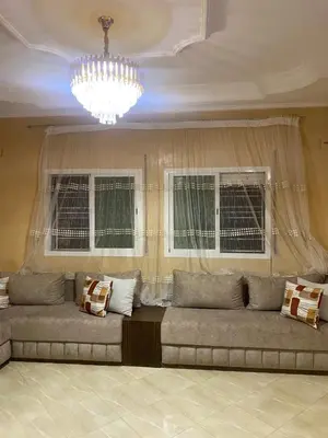 a couch in a living room with two windows at Appartement chez Elmehdi in Fès