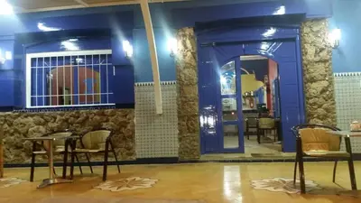 a restaurant with blue walls and chairs and tables at AMRAOUI Apartment in Rissani