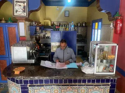 a man sitting at a counter in a kitchen at AMRAOUI Apartment in Rissani