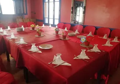 a long table with a red table cloth and red chairs at AMRAOUI Apartment in Rissani