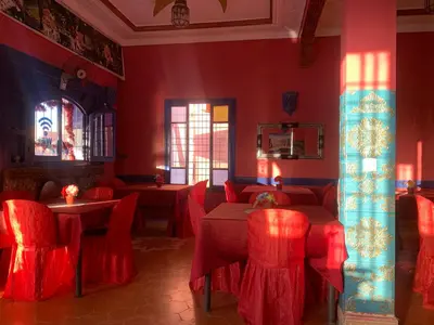 a restaurant with red chairs and tables in a room at AMRAOUI Apartment in Rissani