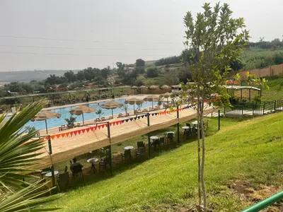 a pool with umbrellas and chairs and a beach at Hotel beaux arts in Meknès