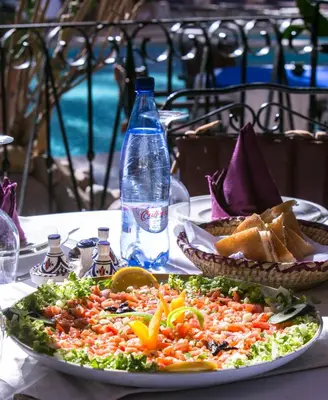 a plate of food with a salad and a bottle of water at Kasbah Sirocco in Zagora