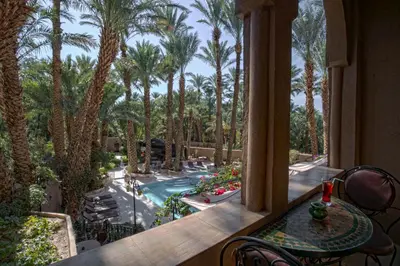 a balcony with a view of a pool and palm trees at Kasbah Sirocco in Zagora