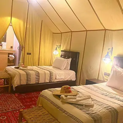 a room with two beds in a tent at Merzouga Sahara Camp in Merzouga
