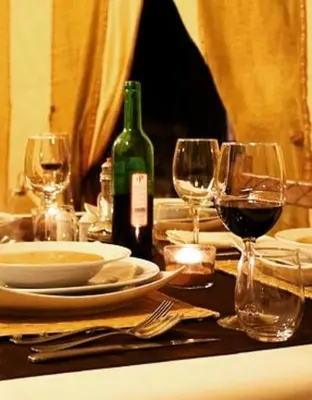 a table with wine glasses and a bottle of wine at Merzouga Sahara Camp in Merzouga