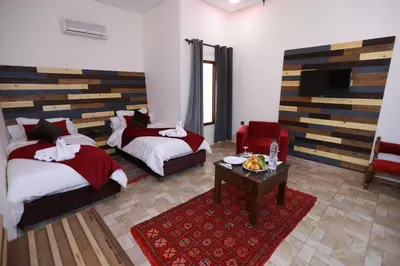 a bedroom with two beds and a table in a room at Kasbah Tizimi in Erfoud