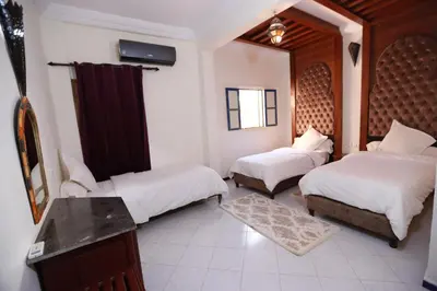 a bedroom with two beds and a table and a mirror at Kasbah Tizimi in Erfoud