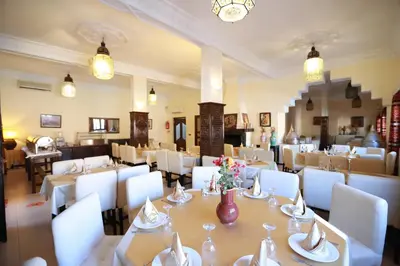 a dining room with white tables and white chairs at Kasbah Tizimi in Erfoud