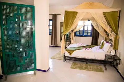 a bedroom with a canopy bed with pink pillows at Kasbah Tizimi in Erfoud