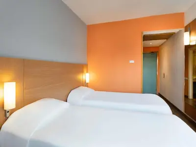 two white beds in a room with orange walls at Ibis Fes in Fès