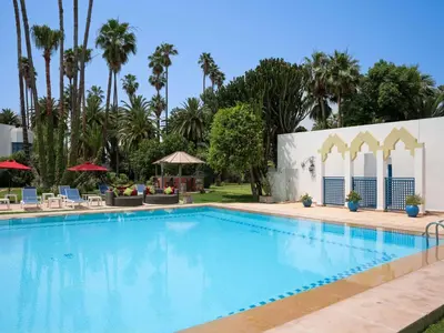 a swimming pool at a resort with palm trees at Ibis Fes in Fès