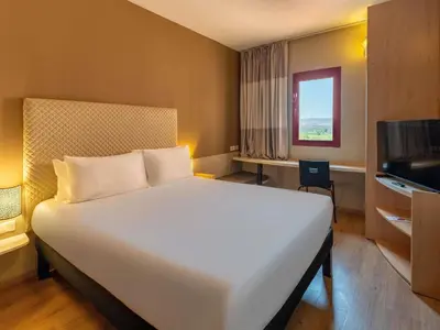 a bedroom with a large white bed and a television at Ibis Ouarzazate Centre in Ouarzazate