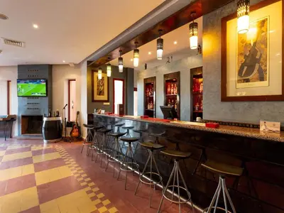 a bar with stools in a room with a tv at Ibis Ouarzazate Centre in Ouarzazate