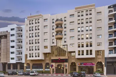 a large white building with cars parked in front of it at Ramada By Wyndham Fes in Fès