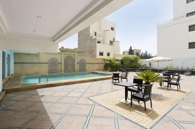 a courtyard with a pool and tables and chairs at Ramada By Wyndham Fes in Fès