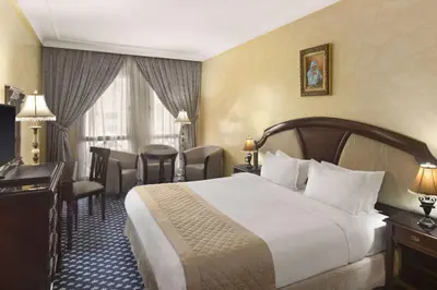 a hotel room with a bed and a table and chairs at Ramada By Wyndham Fes in Fès