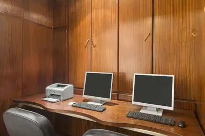 a desk with two monitors and a printer on it at Ramada By Wyndham Fes in Fès