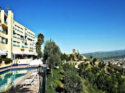 a hotel with a swimming pool next to a building at Les Mérinides in Fès