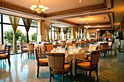 a dining room with tables and chairs and windows at Les Mérinides in Fès