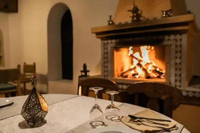 a dining room with a table with a fireplace at Kasbah Mohayut in Merzouga