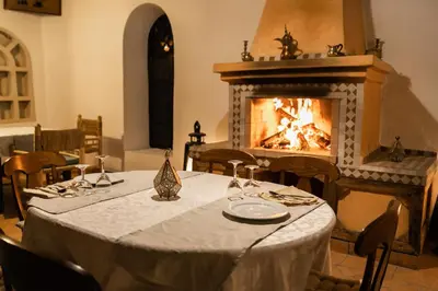 a dining room with a table and a fireplace at Kasbah Mohayut in Merzouga