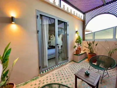 a patio with a table and a room with a bed at Riad Zamane Fès - Boutique & Spa in Fès
