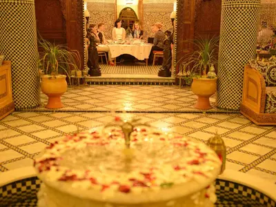 a room with a table and people sitting at a table at Riad El Yacout in Fès