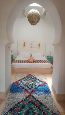 a bedroom with a bed with a rug on the floor at Kasbah ait Moussa in Kalaat MGouna