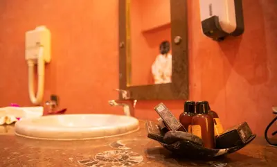 a bathroom with a sink and a person in a mirror at Palais Du Desert Hotel & Spa in Erfoud
