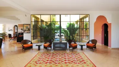 a lobby with chairs and a table and a large window at Riad le Ksar de Fes in Ain Cheggag