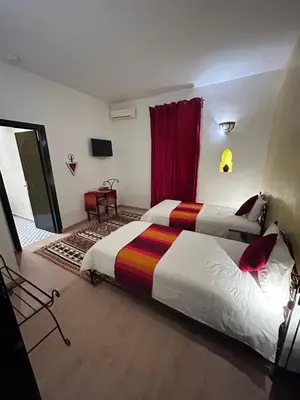 a hotel room with two beds and a window at Riad le Ksar de Fes in Ain Cheggag