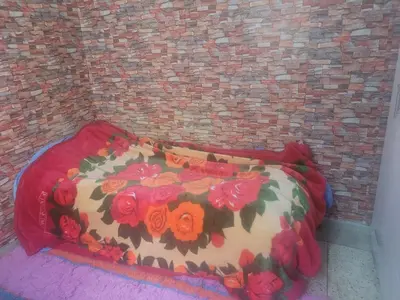 a bed with a floral comforter in front of a brick wall at بيت مع وجبة إفطار لمشجعي كأس الأمم الأفريقية in Fès