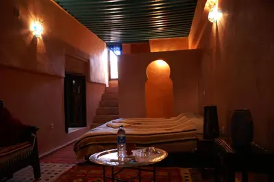 a room with two beds and a table with a bottle on it at Riad Felloussia in Meknès