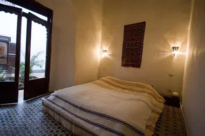 a bedroom with a bed in a room with a window at Riad Felloussia in Meknès